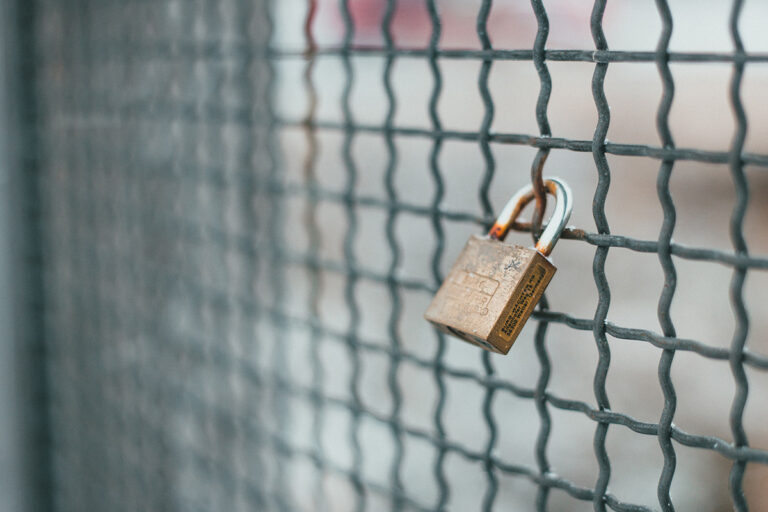 Property Security - image of a metal lock hanging on metal fence